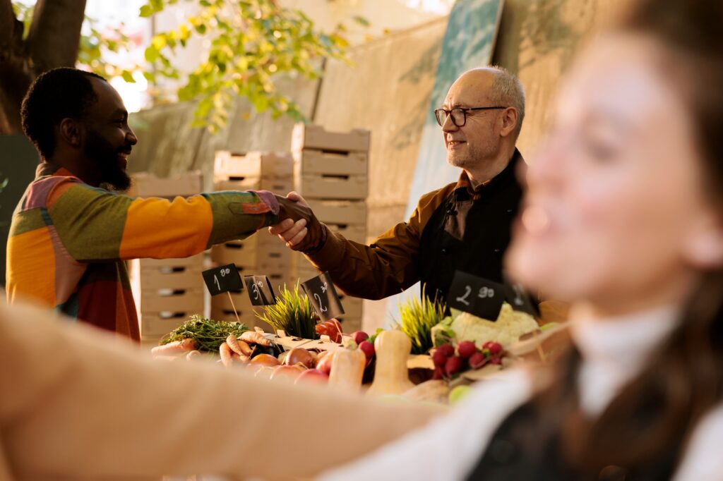 Vendor greets client at food market stand